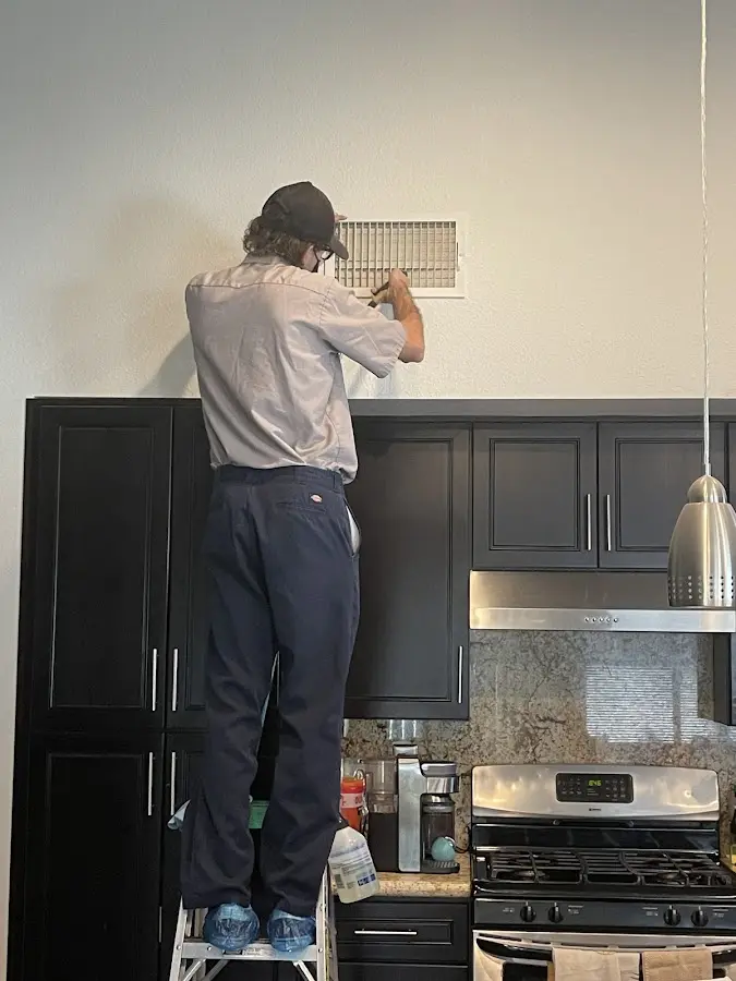 Technician inspecting an air vent during HVAC service in Brookside